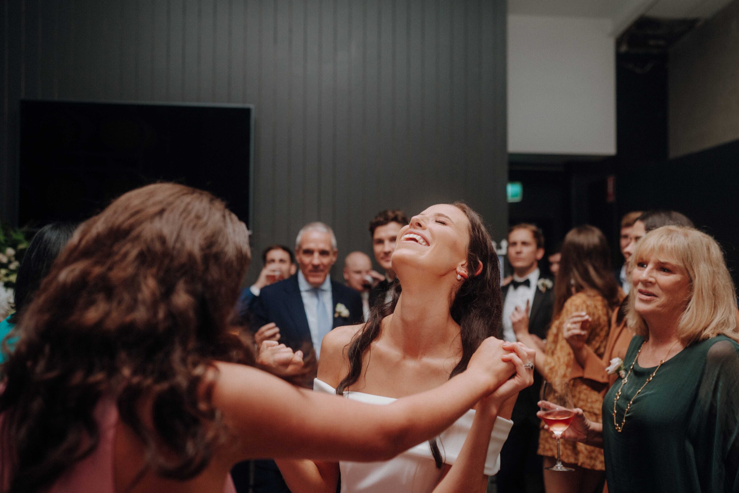 A group of people enjoying a celebration indoors. A woman in the center smiles while others watch.