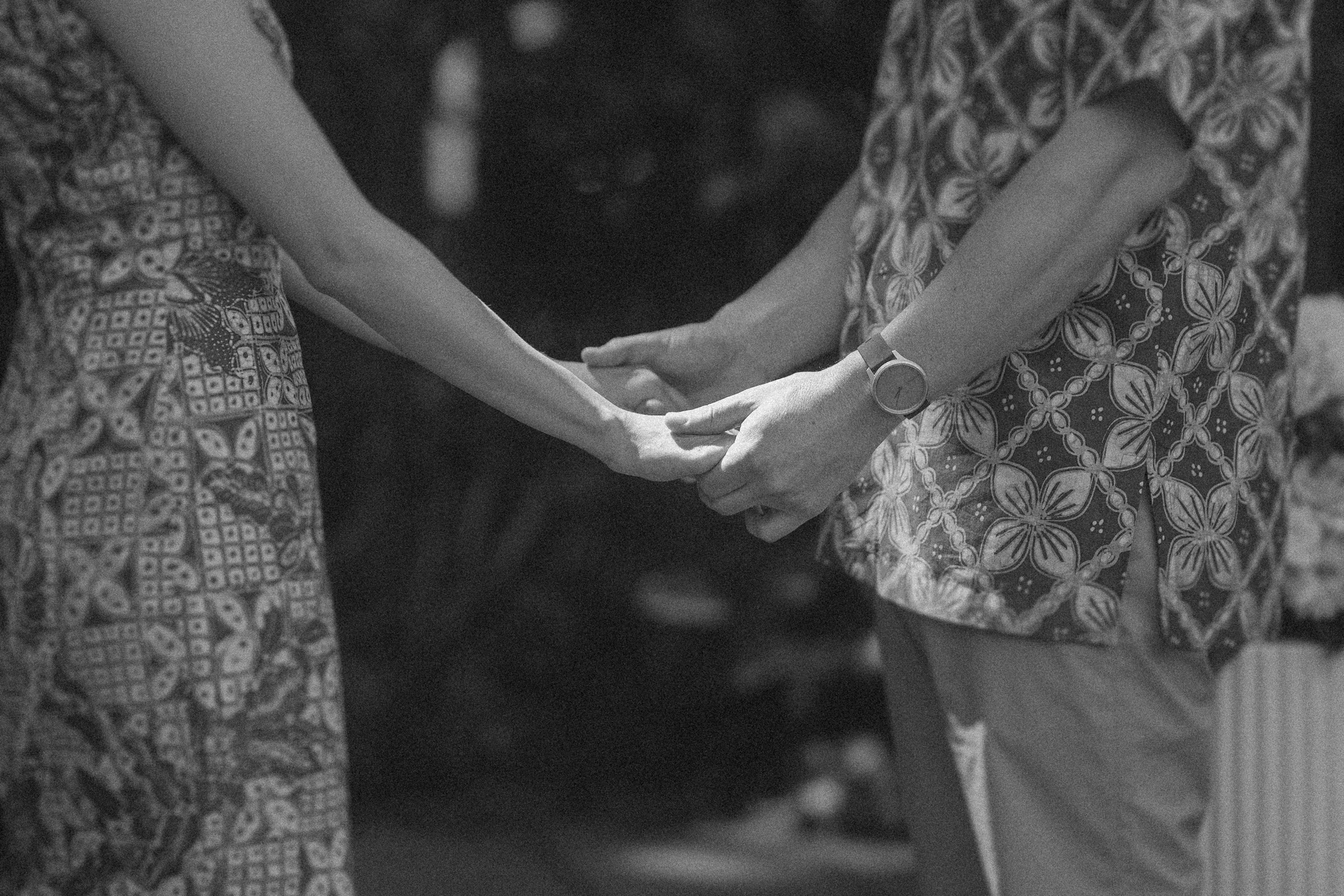 Two people holding hands, wearing patterned outfits.